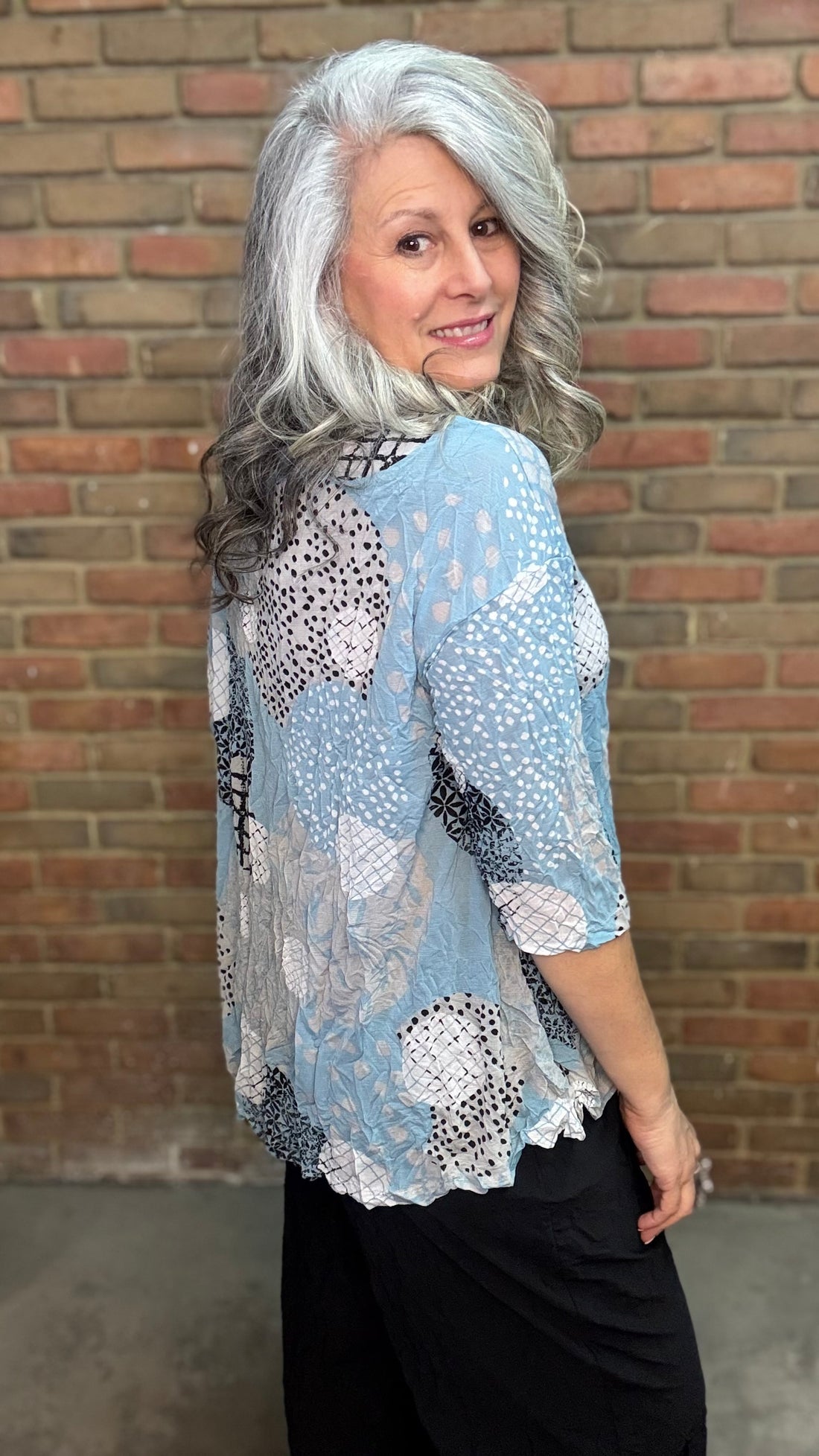 Woman wearing Laurie Top - Sky against a brick wall