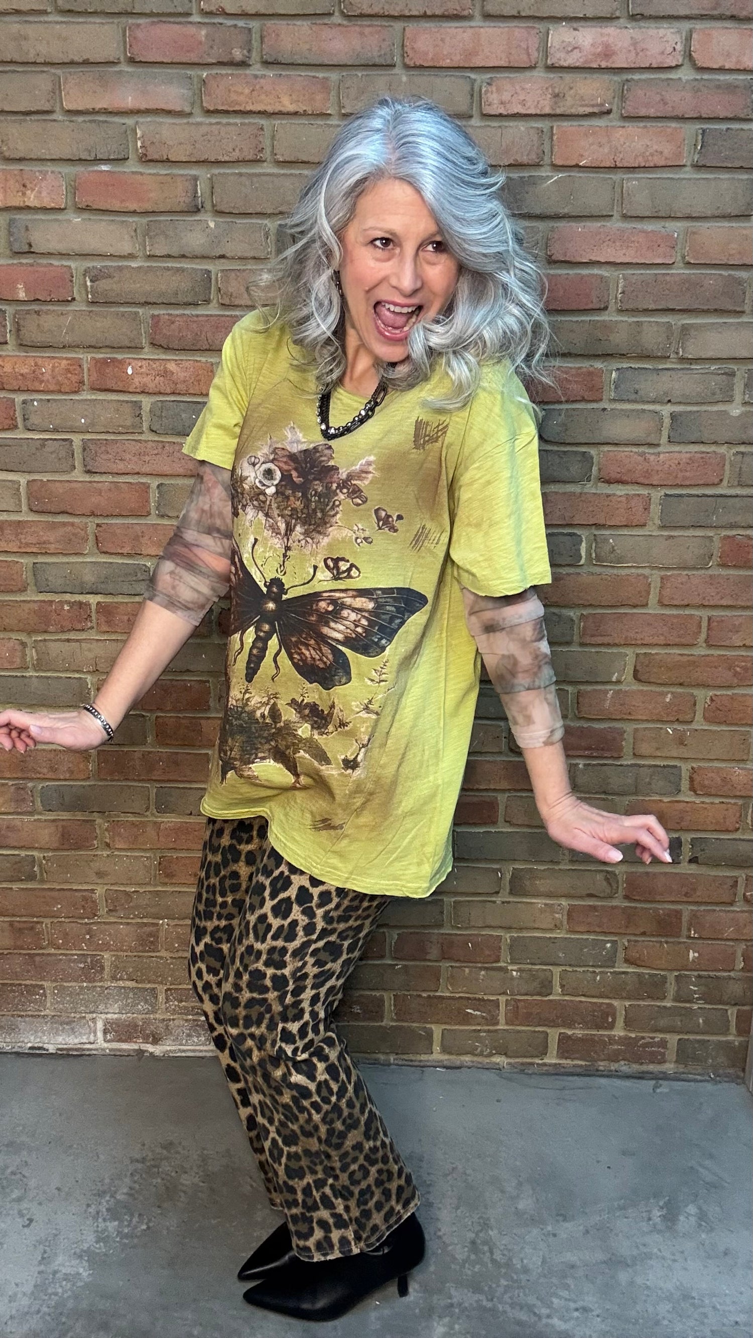 Woman wearing Moon Dance Tee - Evening Stop in front of a brick wall.