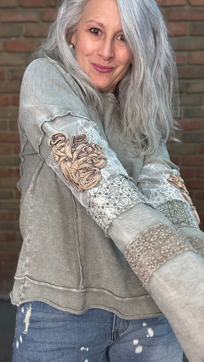 Woman wearing the Olive Embellished Sleeve Top and Bleached Wide Leg Jeans standing against a brick wall.