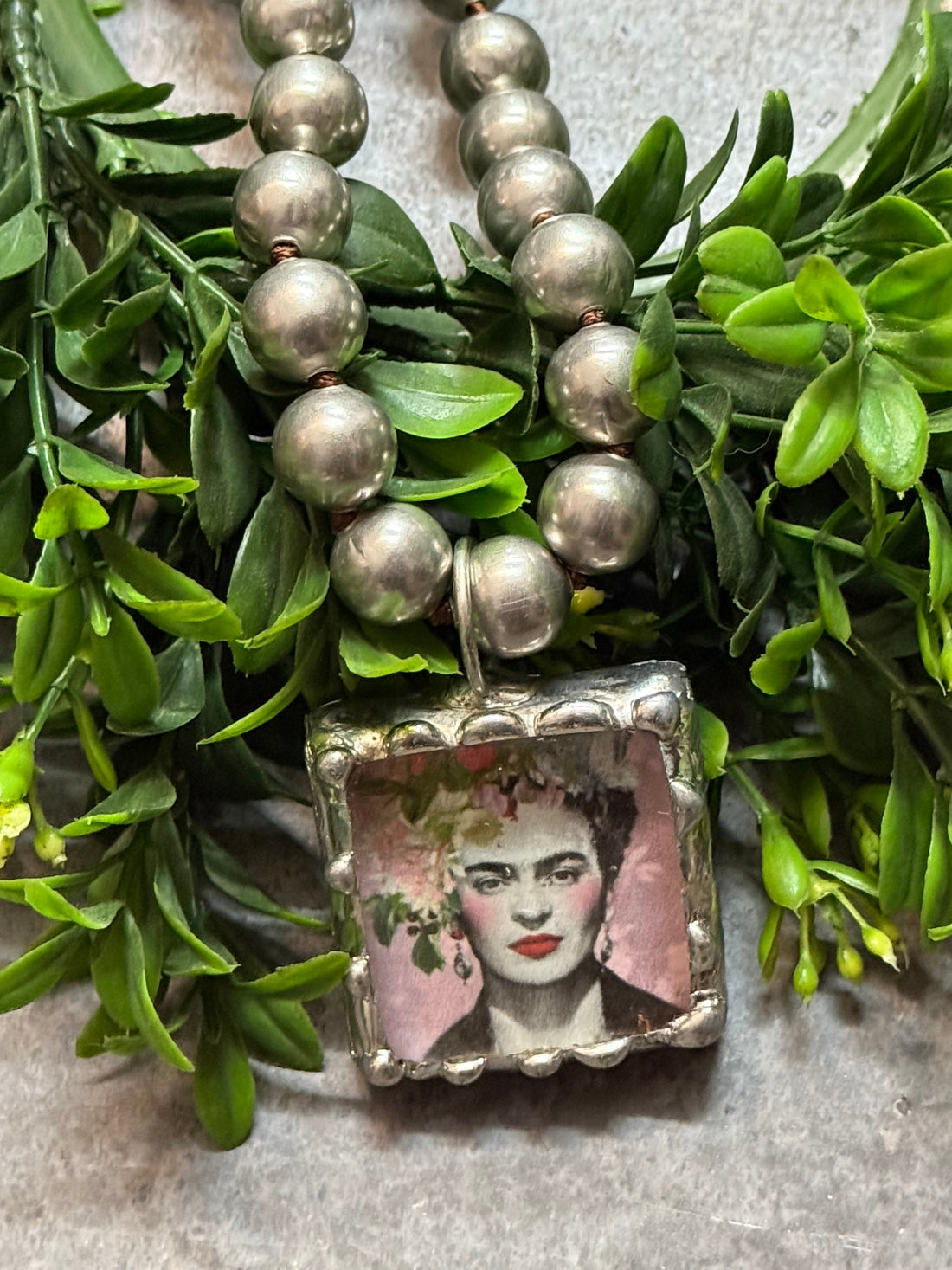Necklace with a pendant featuring a portrait on green leaves