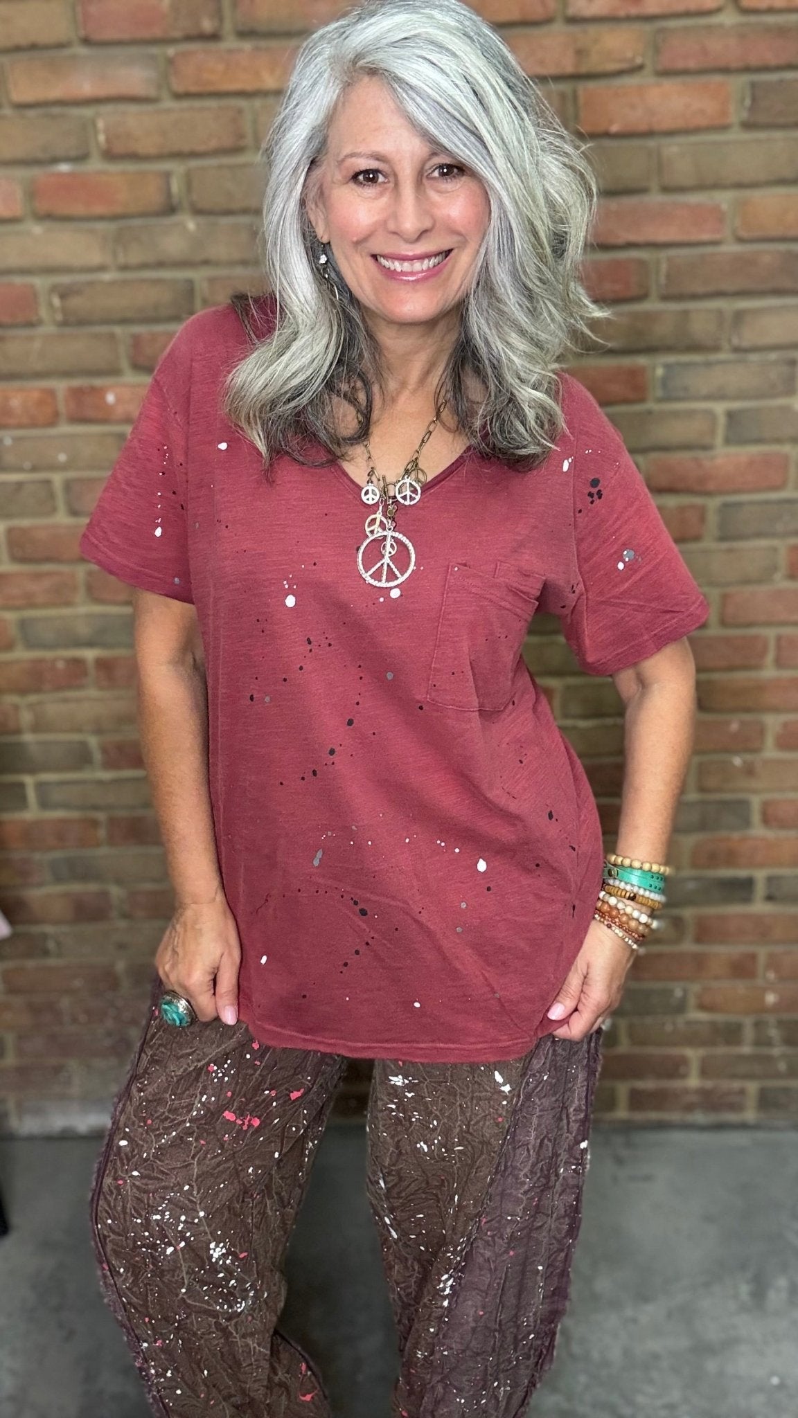 Woman in red shirt in front of brick wall.