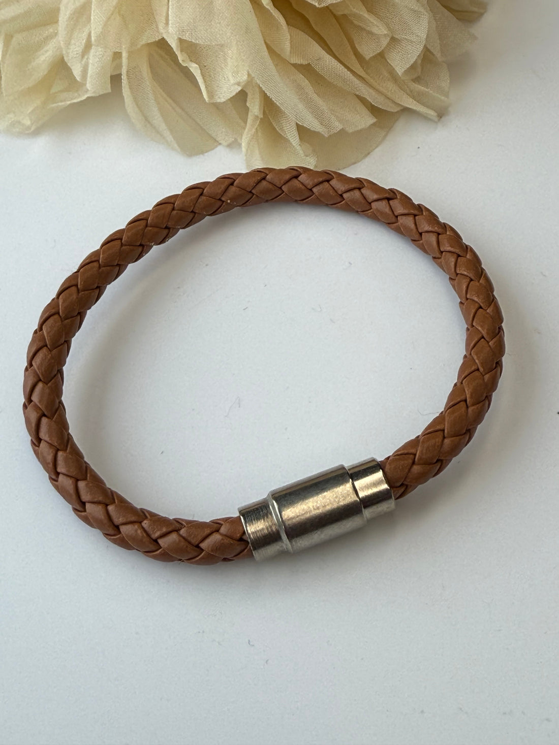Camel color braided leather bracelet with a silver clasp on a white background