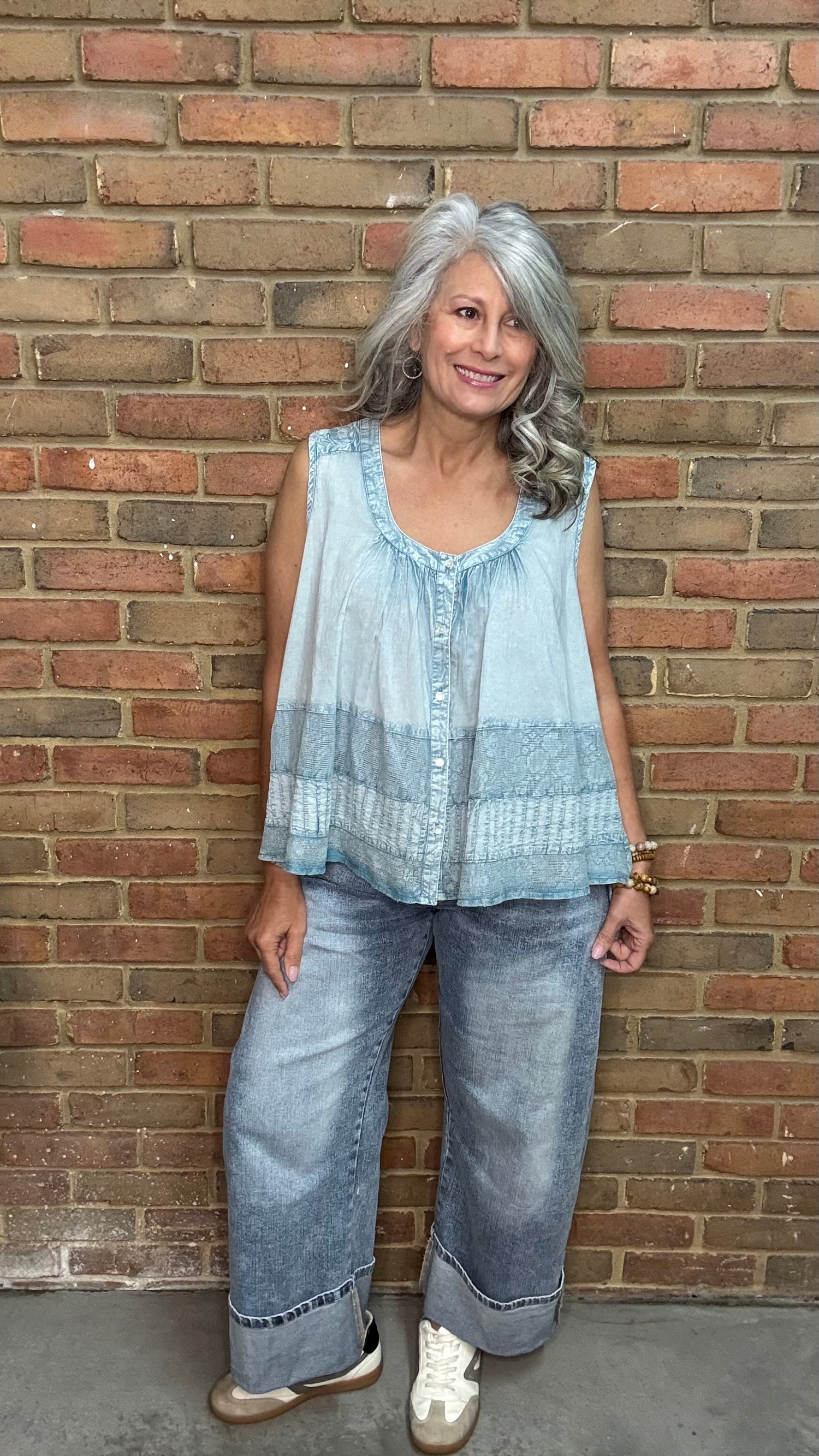 Woman wearing the Denim Blue Crochet Contrast Tank Top, a light blue sleeveless top and jeans standing against a brick wall.