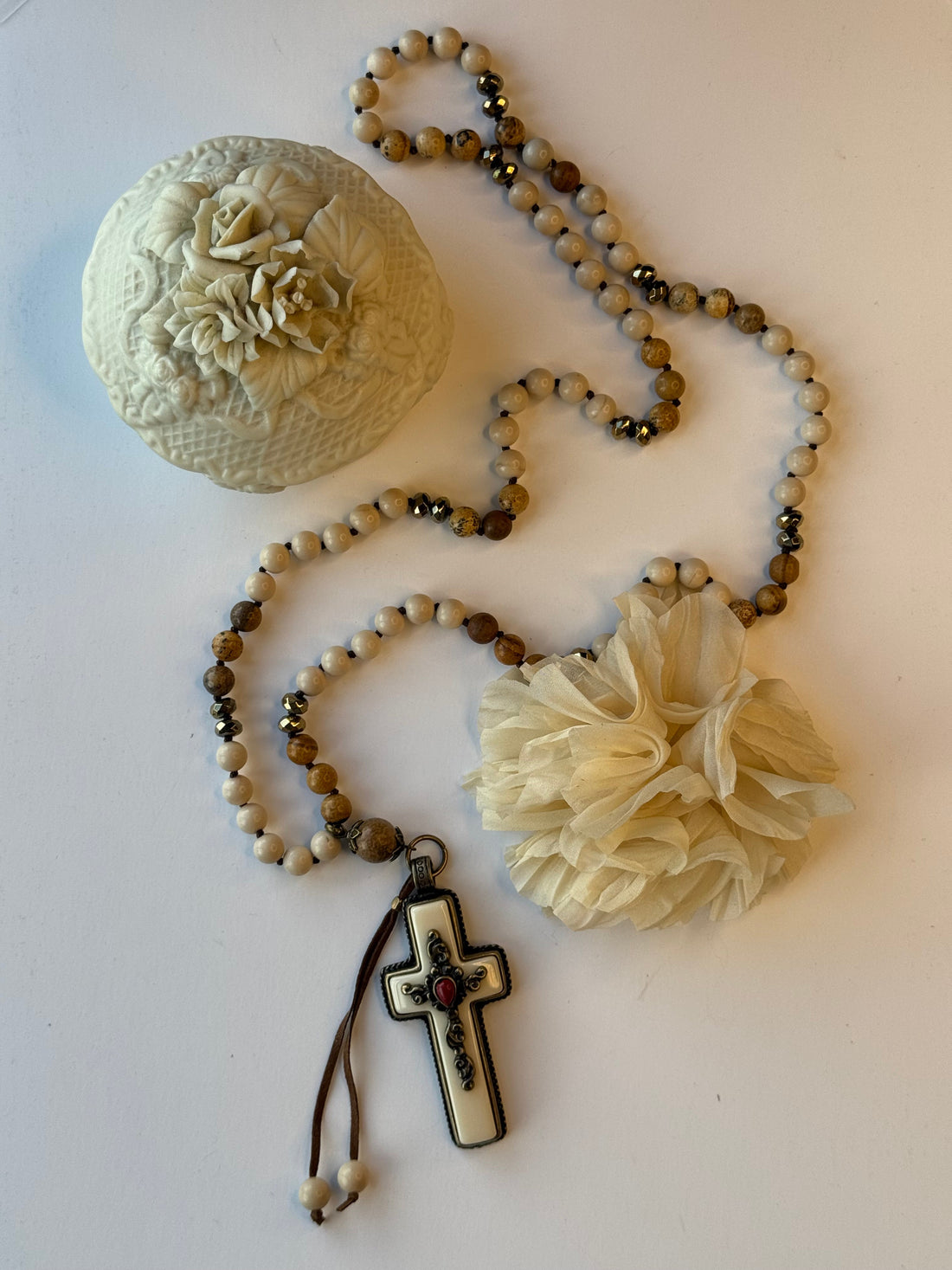 Necklace with beads, floral elements, and a cross pendant on a light background