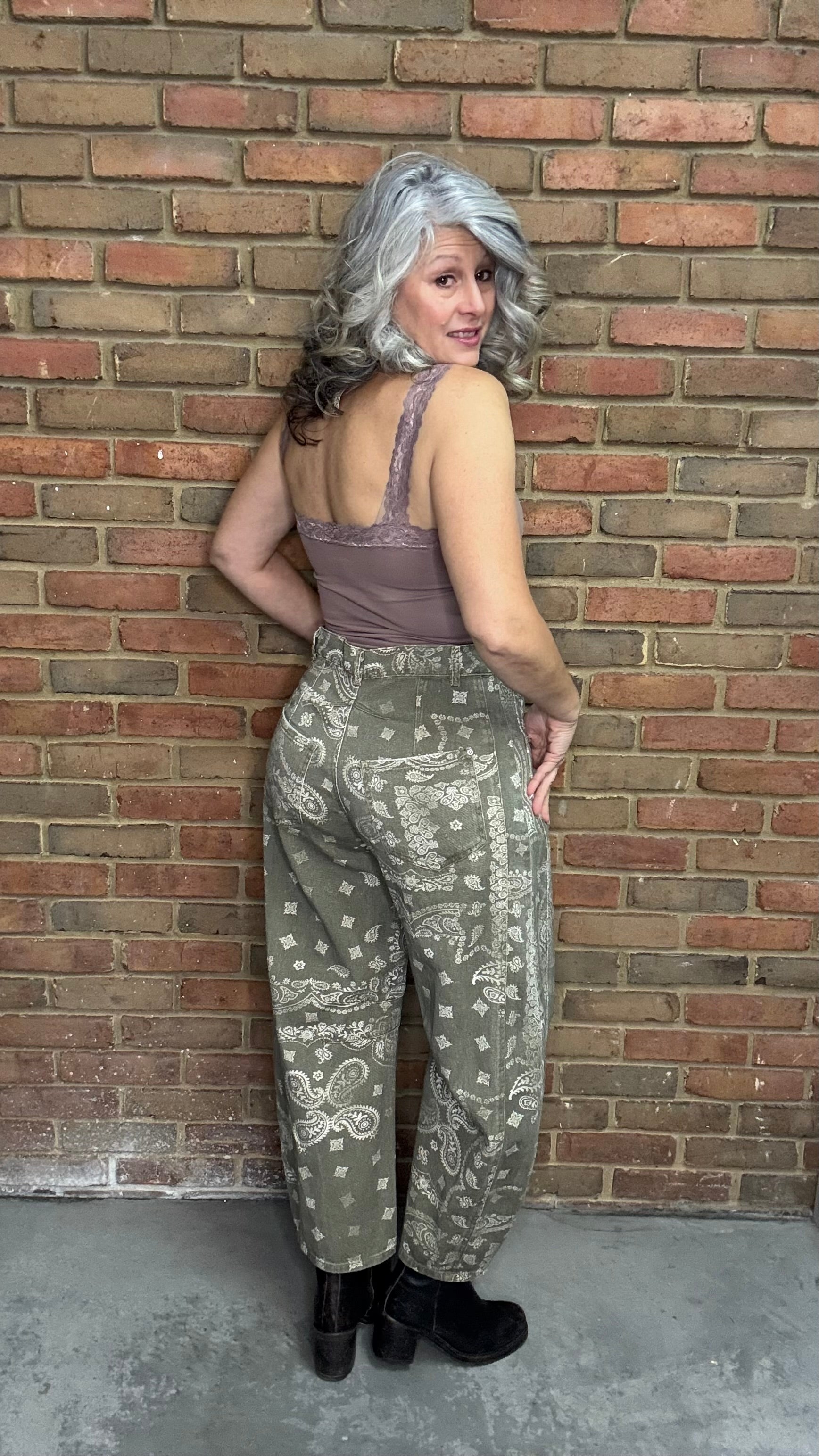 Woman wearing Lace Camisole and the Paisley Print Jean standing against a brick wall.
