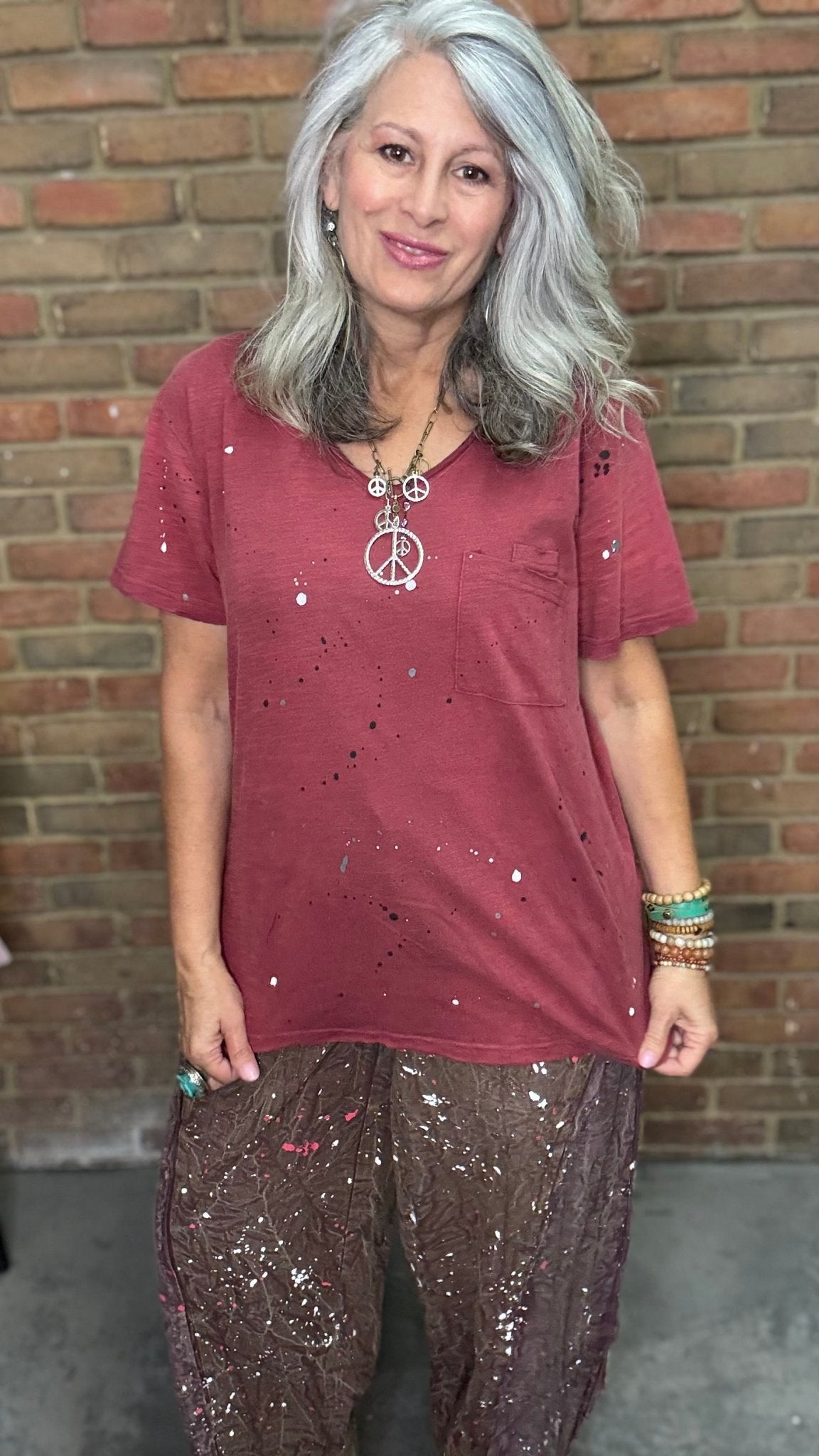 Woman in red shirt in front of brick wall.