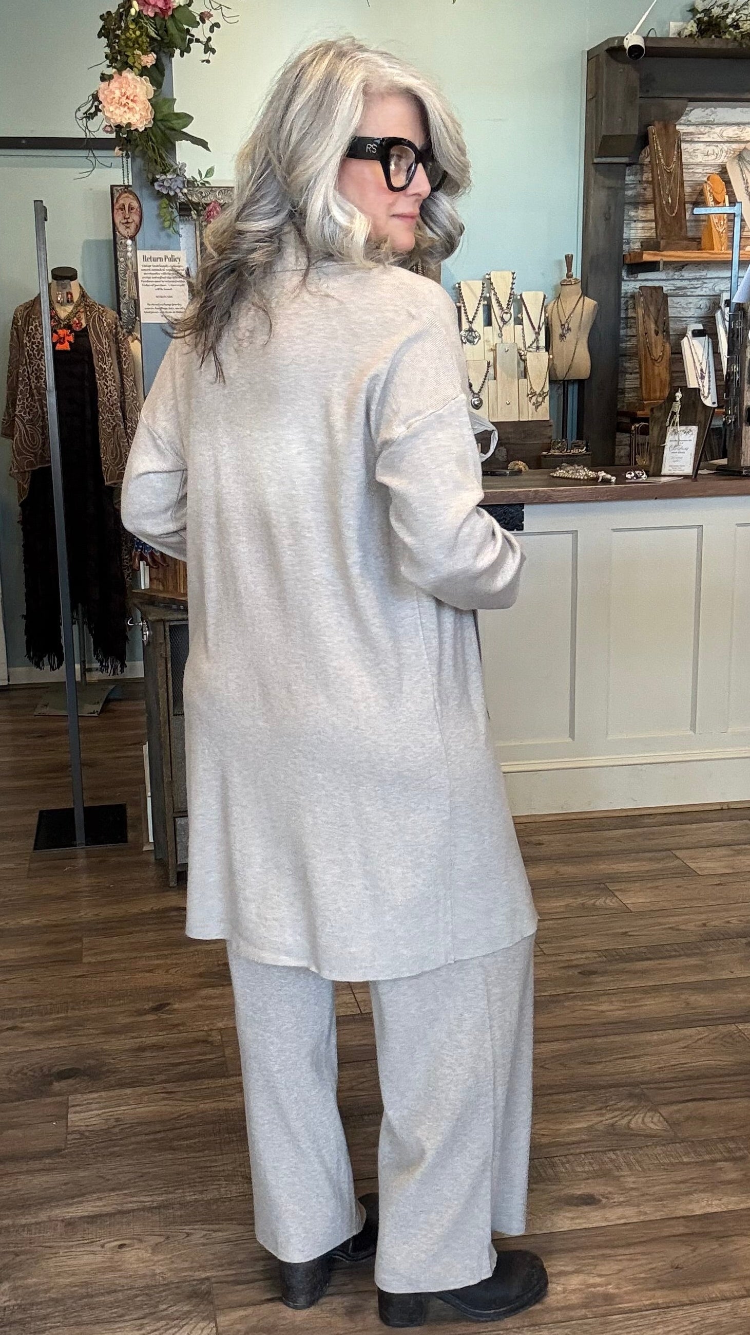 Person wearing a light Khaki outfit in a store setting with mannequins and clothing racks.