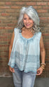 Woman wearing the Denim Blue Crochet Contrast Tank Top, a light blue sleeveless top and jeans standing against a brick wall.