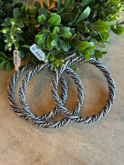 Silver Twist Bangle Bracelet on a textured surface with greenery.