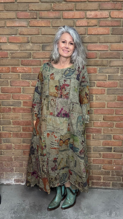 Woman wearing a patterned dress and green boots standing against a brick wall.