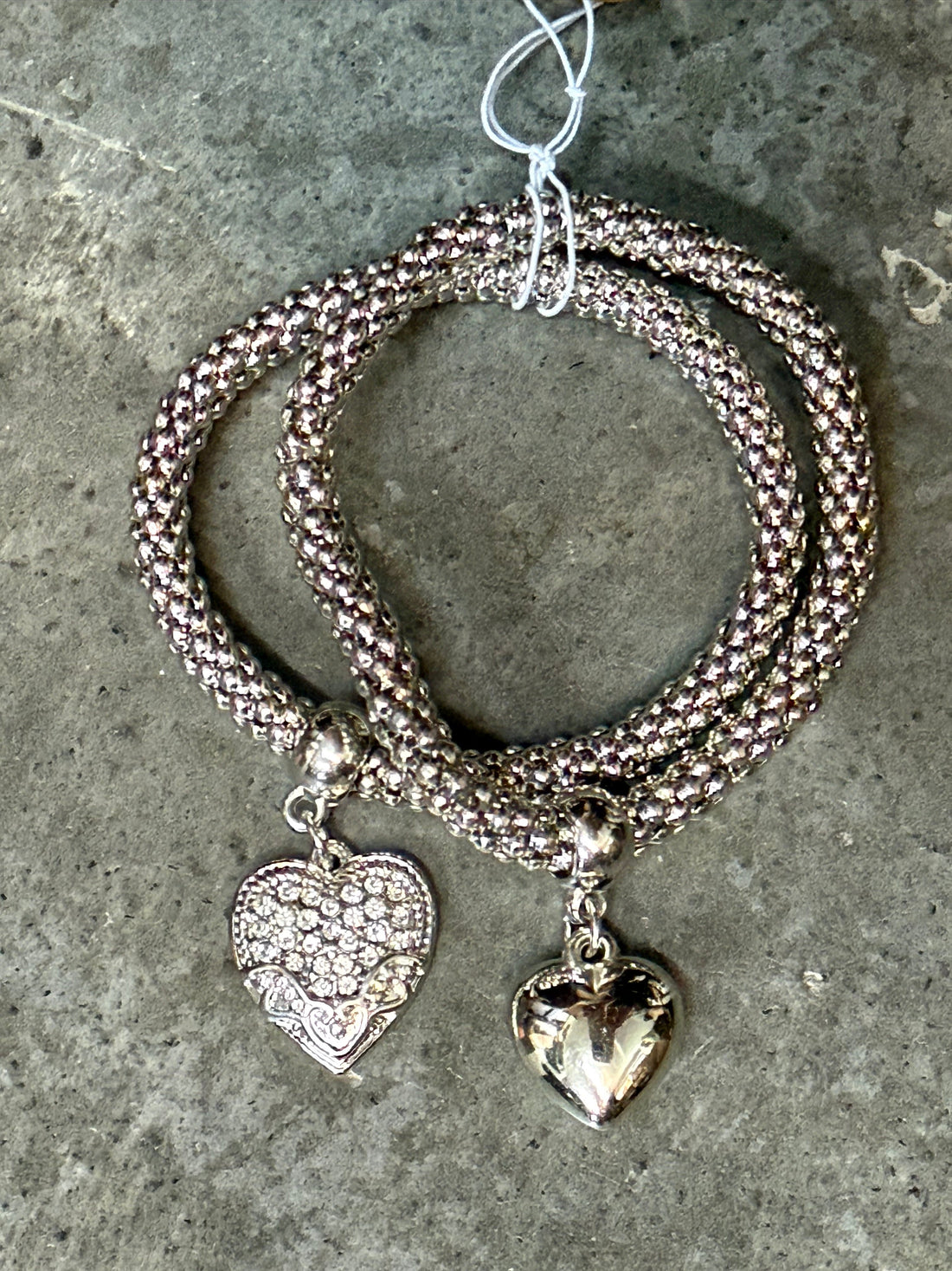 Silver bracelet with heart-shaped pendants on a textured surface