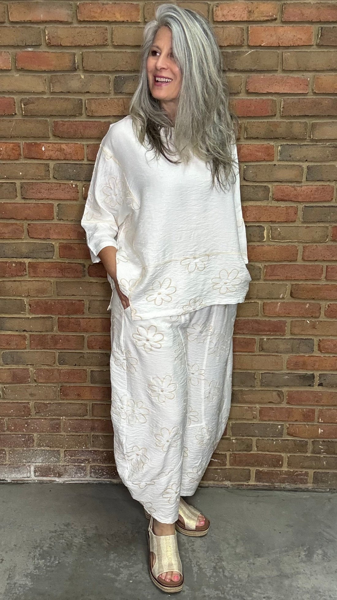 Woman in the Daisy Pant and Top Set standing against a brick wall