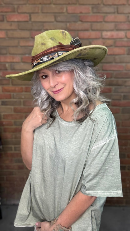 Woman wearing Spirit Feather Hat against a brick wall.