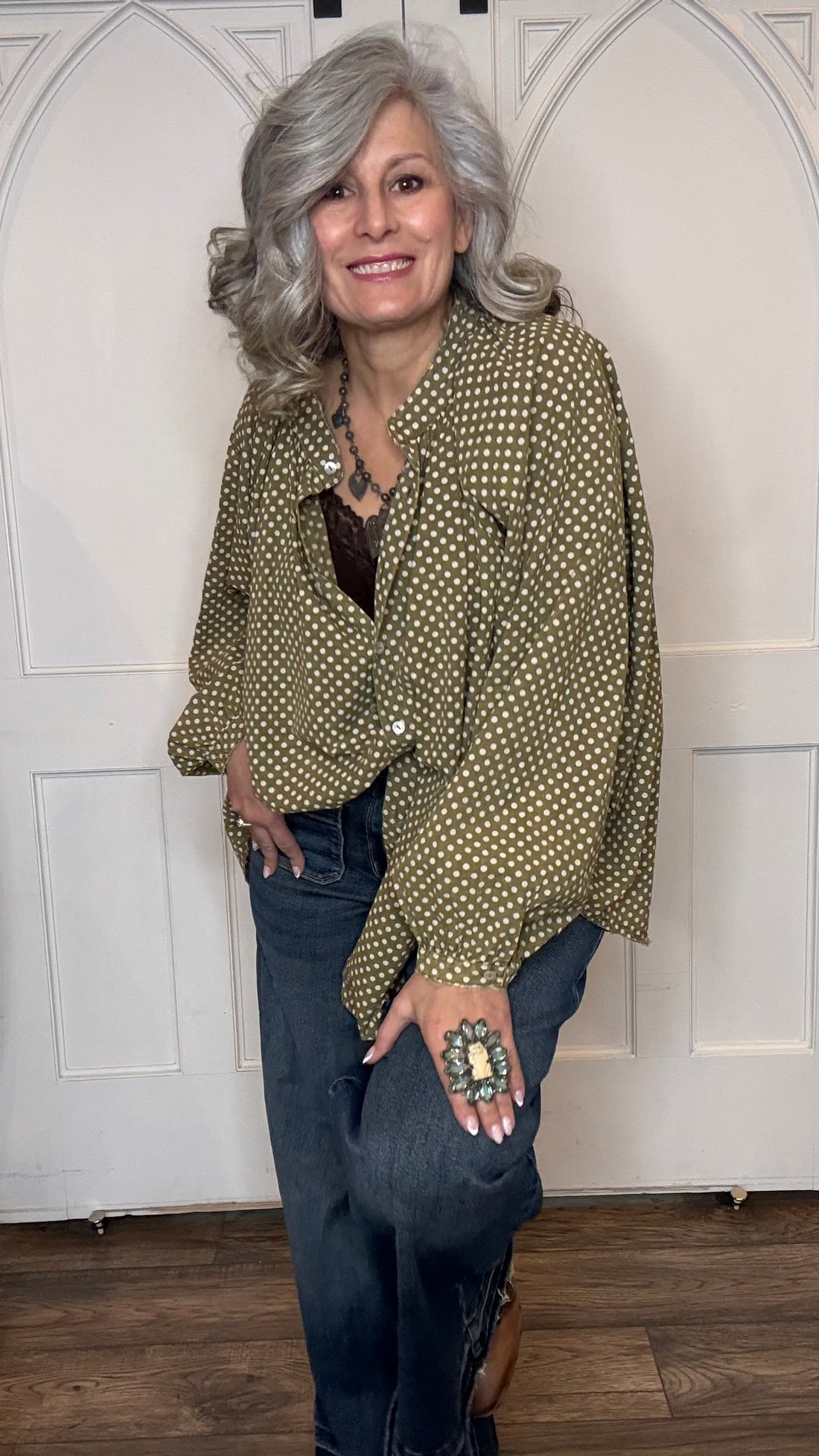 Woman wearing the Sweet Nothings Top-Olive Dot and Judy Blue Palazzo jeans standing against a white paneled wall.