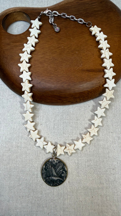 Star-shaped necklace with a coin pendant on a wooden surface