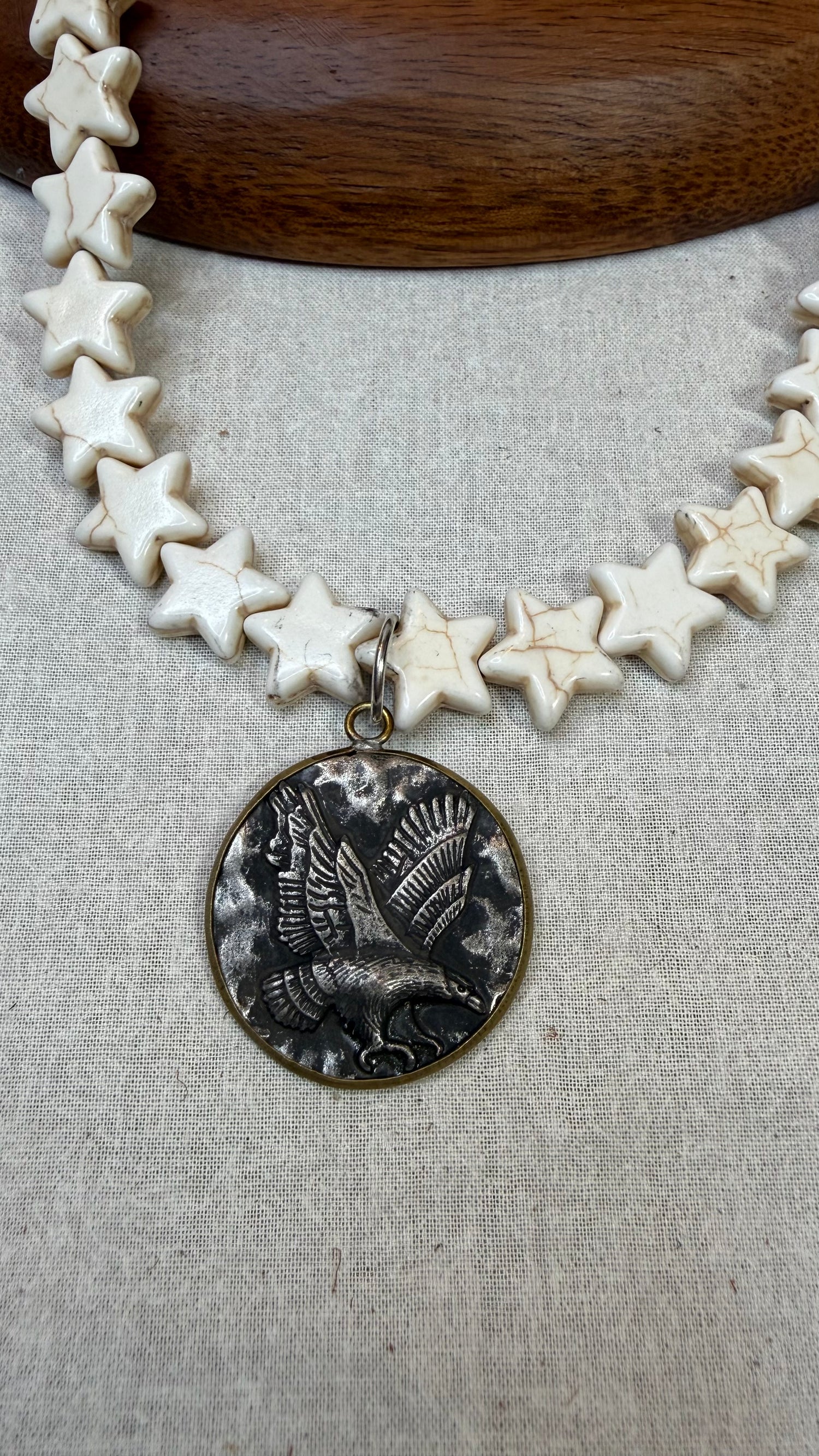 Necklace with star-shaped beads and a detailed pendant on a textured surface
