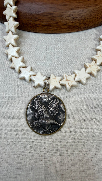 Necklace with star-shaped beads and a detailed pendant on a textured surface