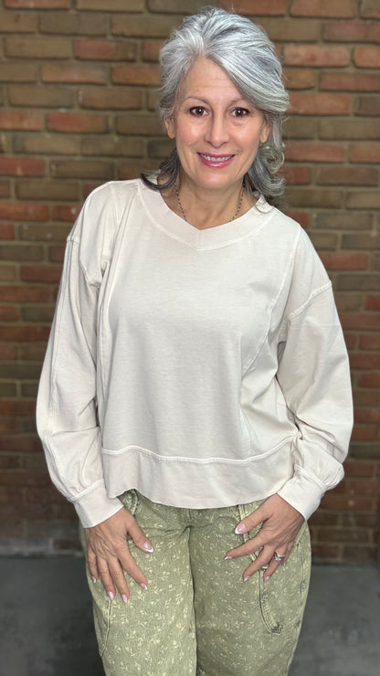 Woman standing against a brick wall wearing the Taupe Long Sleeve Top and Floral Printed Barrel Pants.