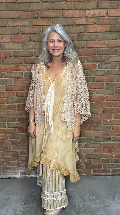 Woman wearing the crochet Forever Timeless Split Tails Jacket over the Wandering Spirit Dress with striped pants standing against a brick wall.