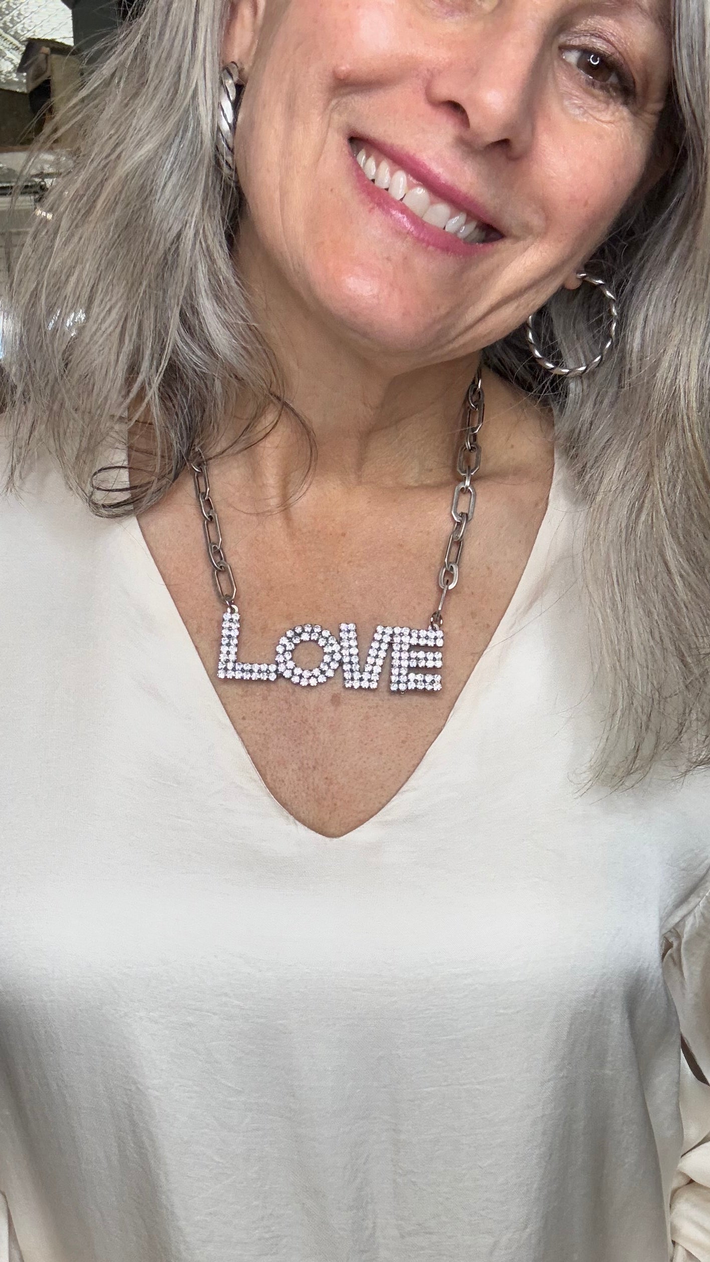 Woman with twisted hoop earrings and a LOVE necklace
