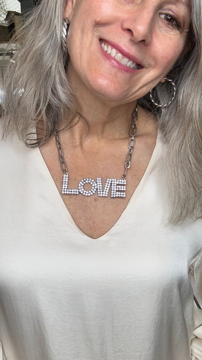Woman with twisted hoop earrings and a LOVE necklace