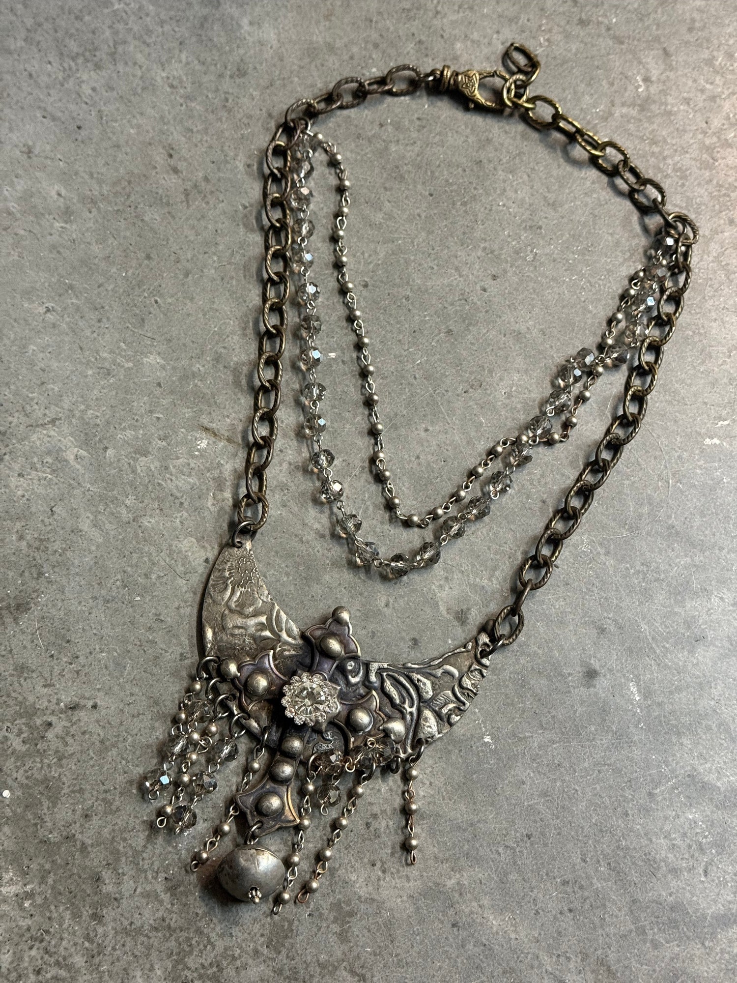 Vintage-style necklace with intricate design on a concrete surface