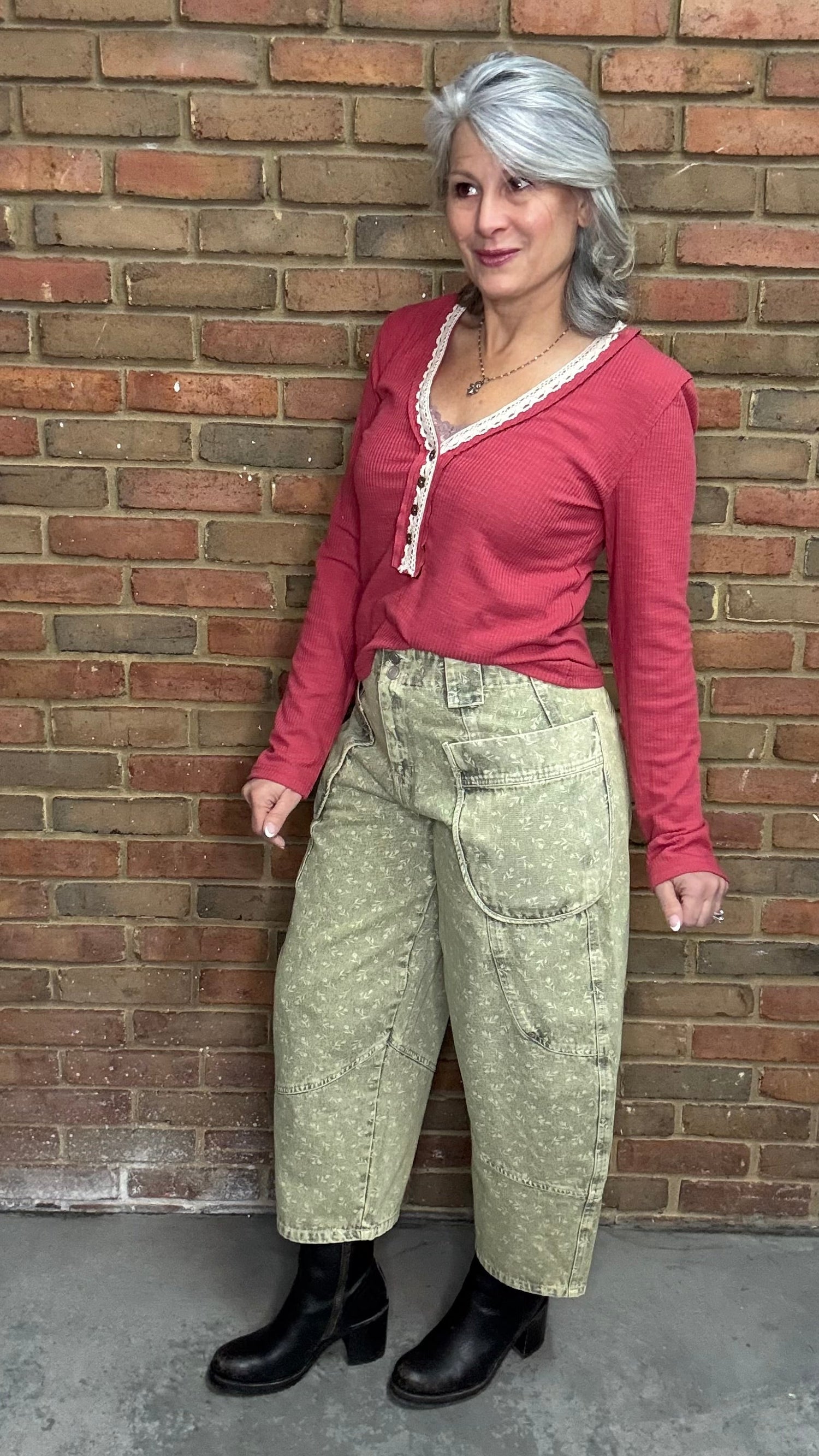 Person wearing the Raspberry Rose Ribbed Henley long-sleeve Top with the Floral Printed Barrel Pants against a brick wall.