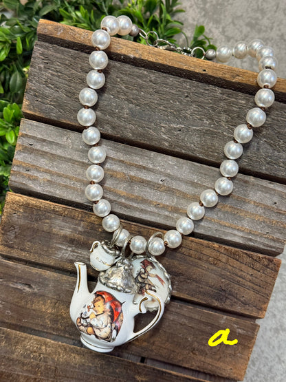 Pearl necklace with a silver teapot charm on a wooden surface
