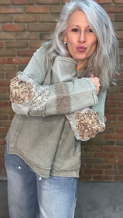 Woman wearing the Olive Embellished Sleeve Top and Bleached Wide Leg Jeans standing against a brick wall.