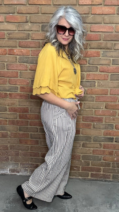 Woman in a mustard and Latte Wide Leg Pull On Pant standing against a brick wall.