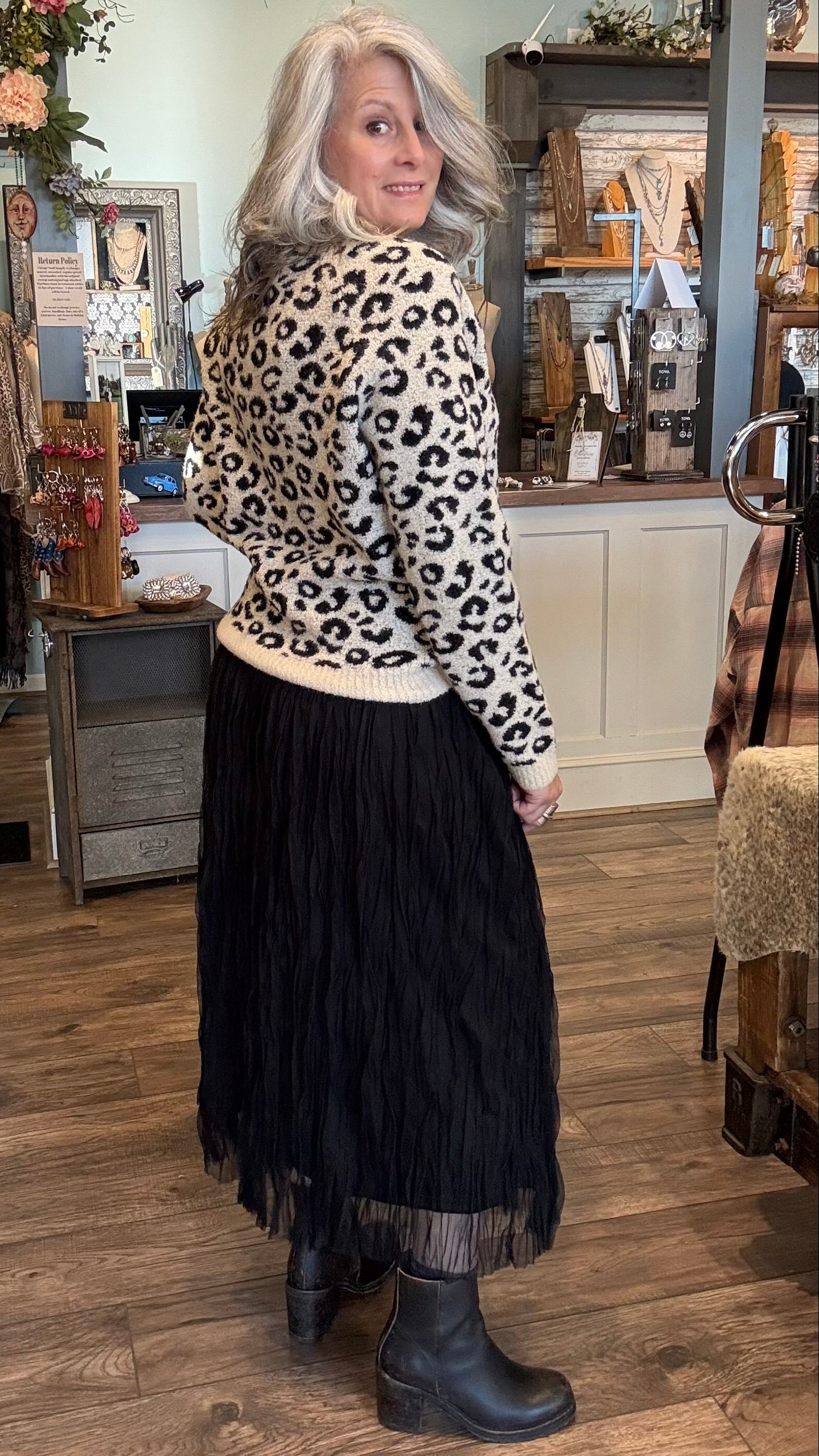 Woman wearing a leopard print sweater and black skirt in a store setting