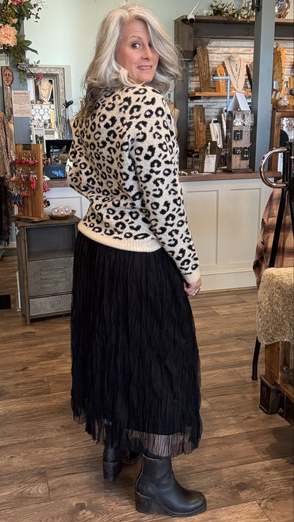 Woman wearing a leopard print sweater and black skirt in a store setting