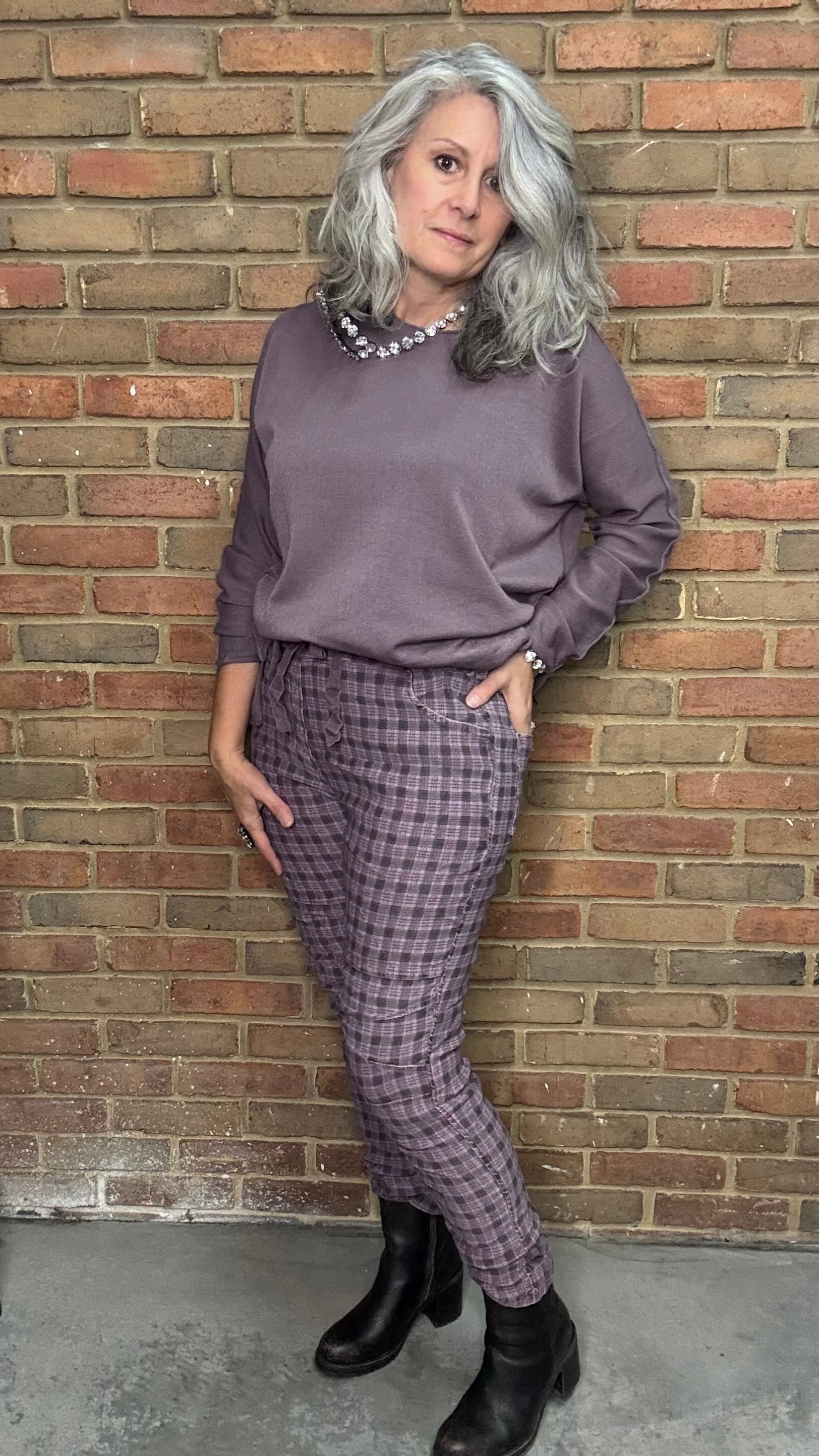 Woman in a purple outfit standing against a brick wall