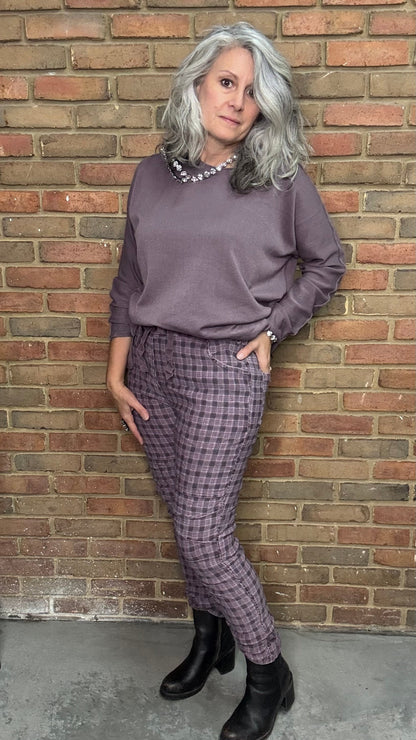 Woman in a purple outfit standing against a brick wall