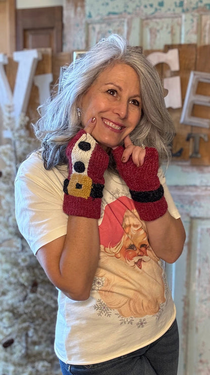 Woman wearing a white shirt with a graphic design, dark pants, and red fingerless gloves in a rustic indoor setting.