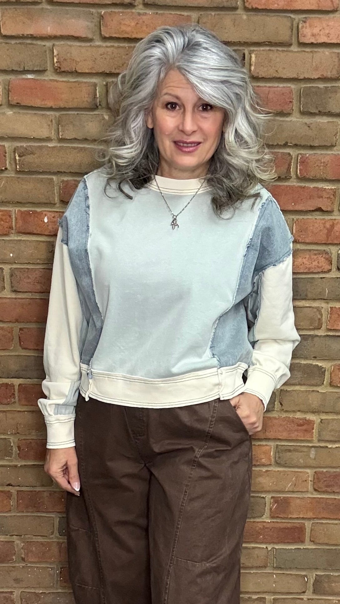 Person wearing the Color Block Pullover Top and the brown pullon barrel pants standing against a brick wall.