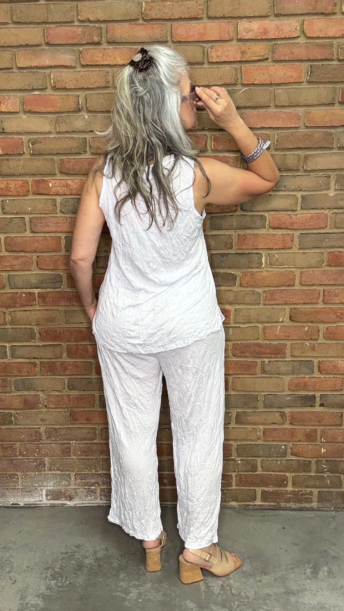 Woman wearing White Capri Straight Leg Pant standing against a brick wall.