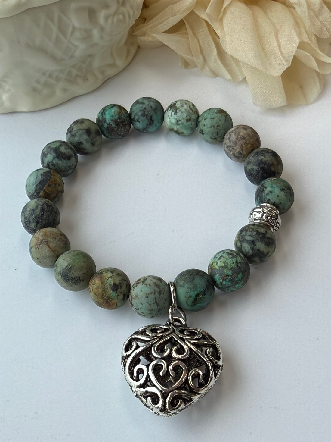 Green beaded bracelet with a silver bead on a white background