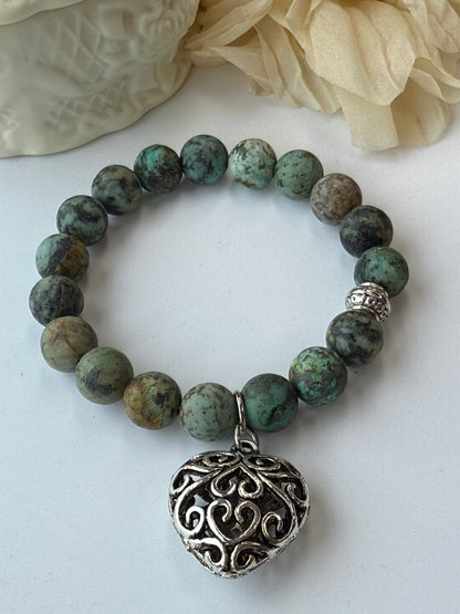 Green beaded bracelet with a silver bead on a white background