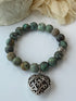 Green beaded bracelet with a silver bead on a white background