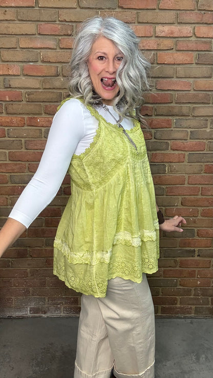 Woman wearing Eyelet Lace Tank over a white shirt, standing against a brick wall.