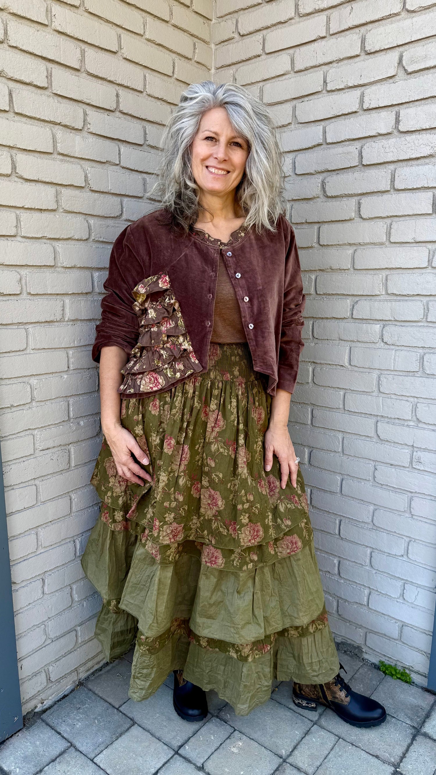 Woman in a layered outfit standing against a brick wall