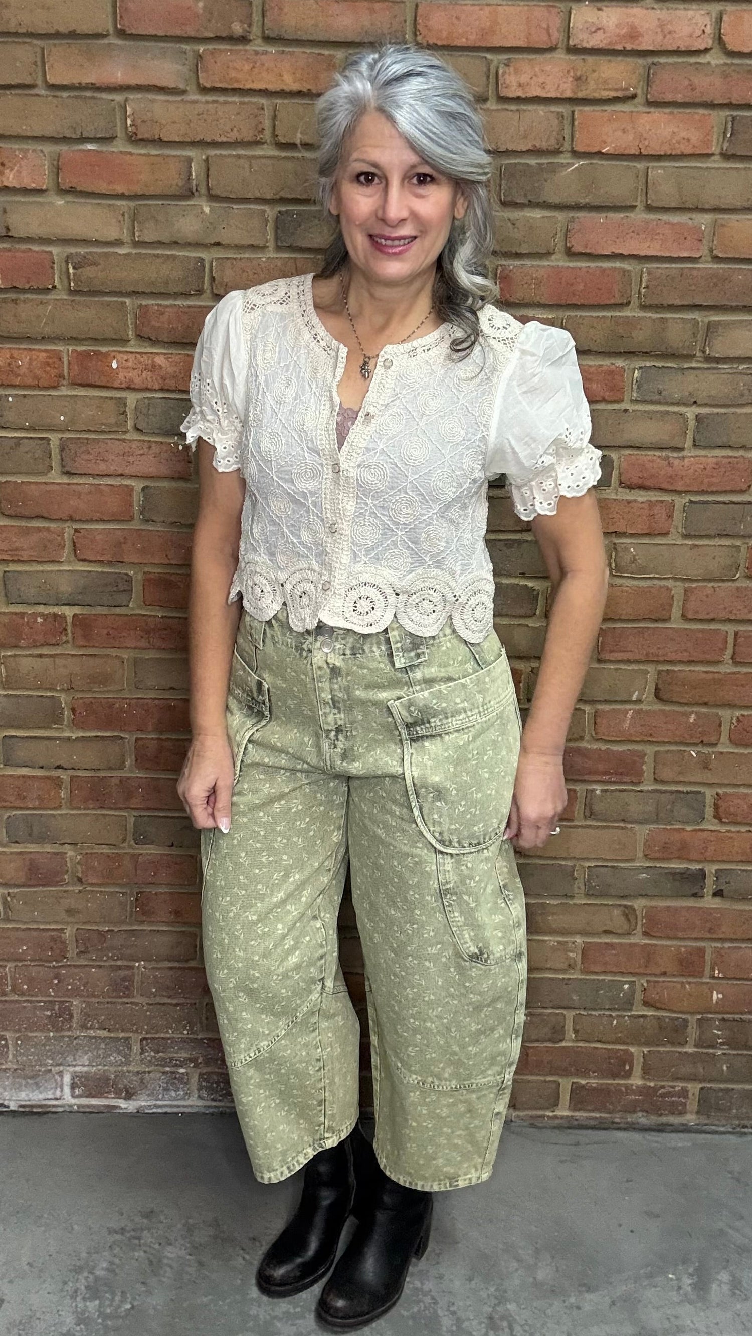 Woman wearing the Crochet Embroidery Button-Up Top and Floral Printed Barrel Pants with a brick wall background