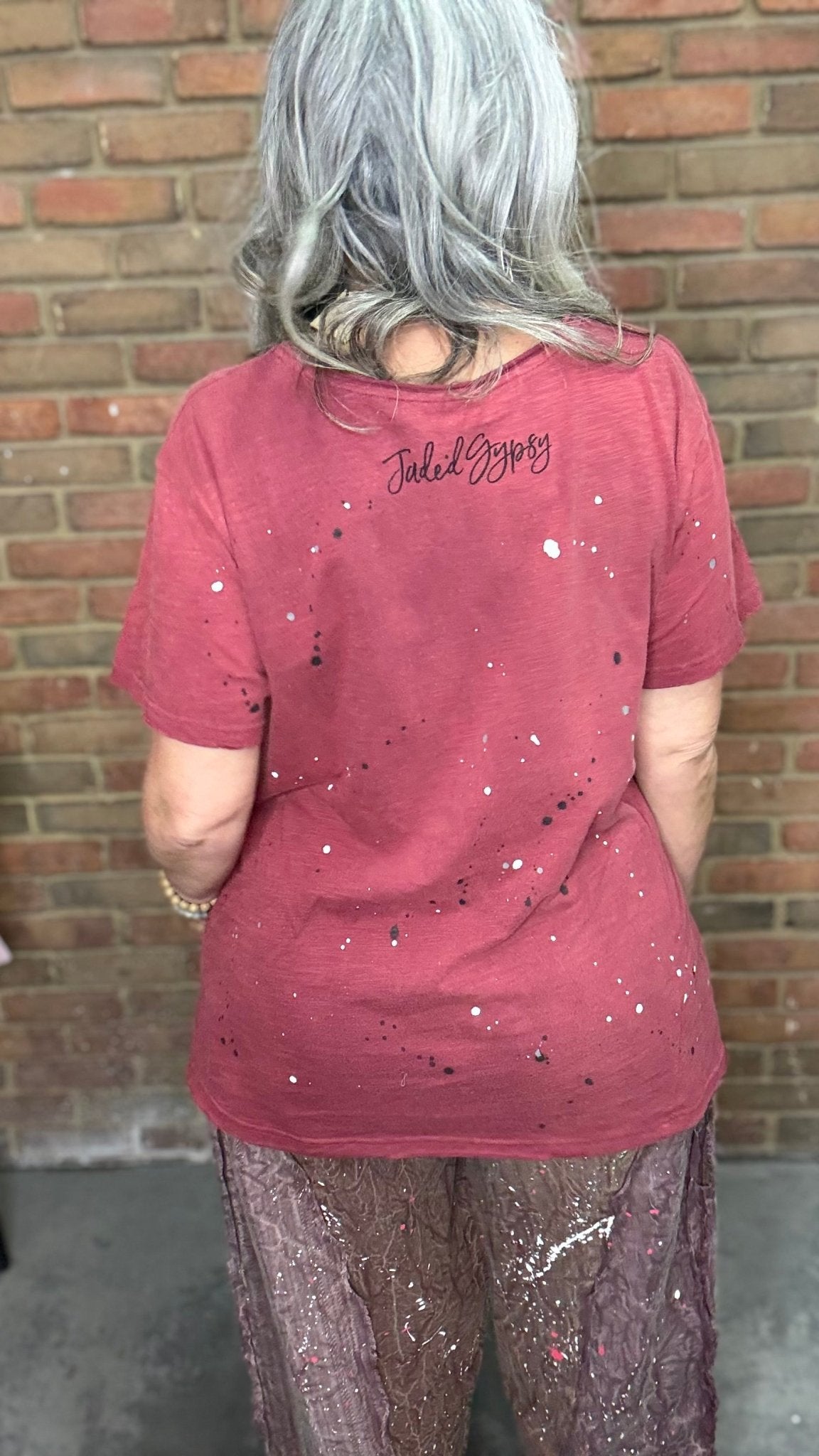 Woman in red shirt in front of brick wall.