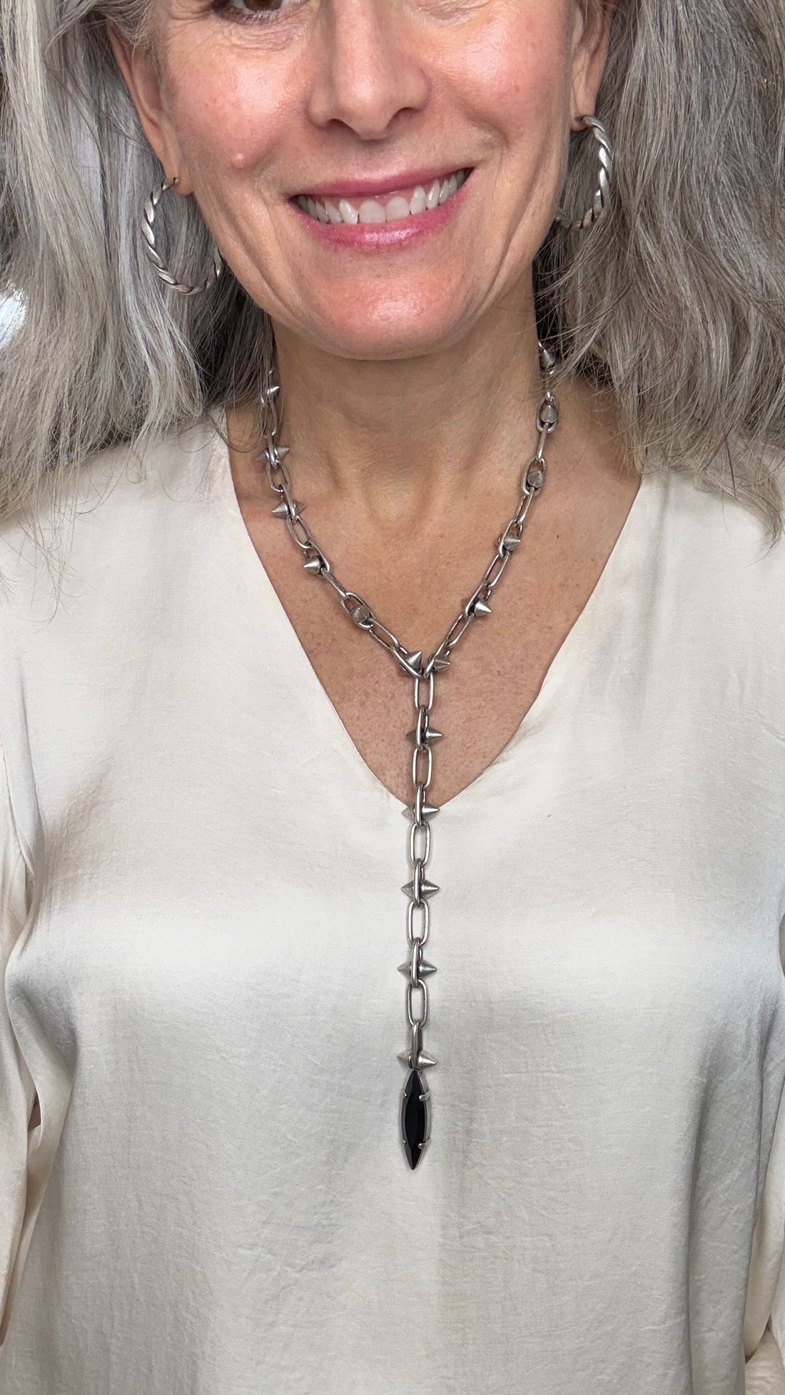 Woman wearing a white dress with a unique necklace design.