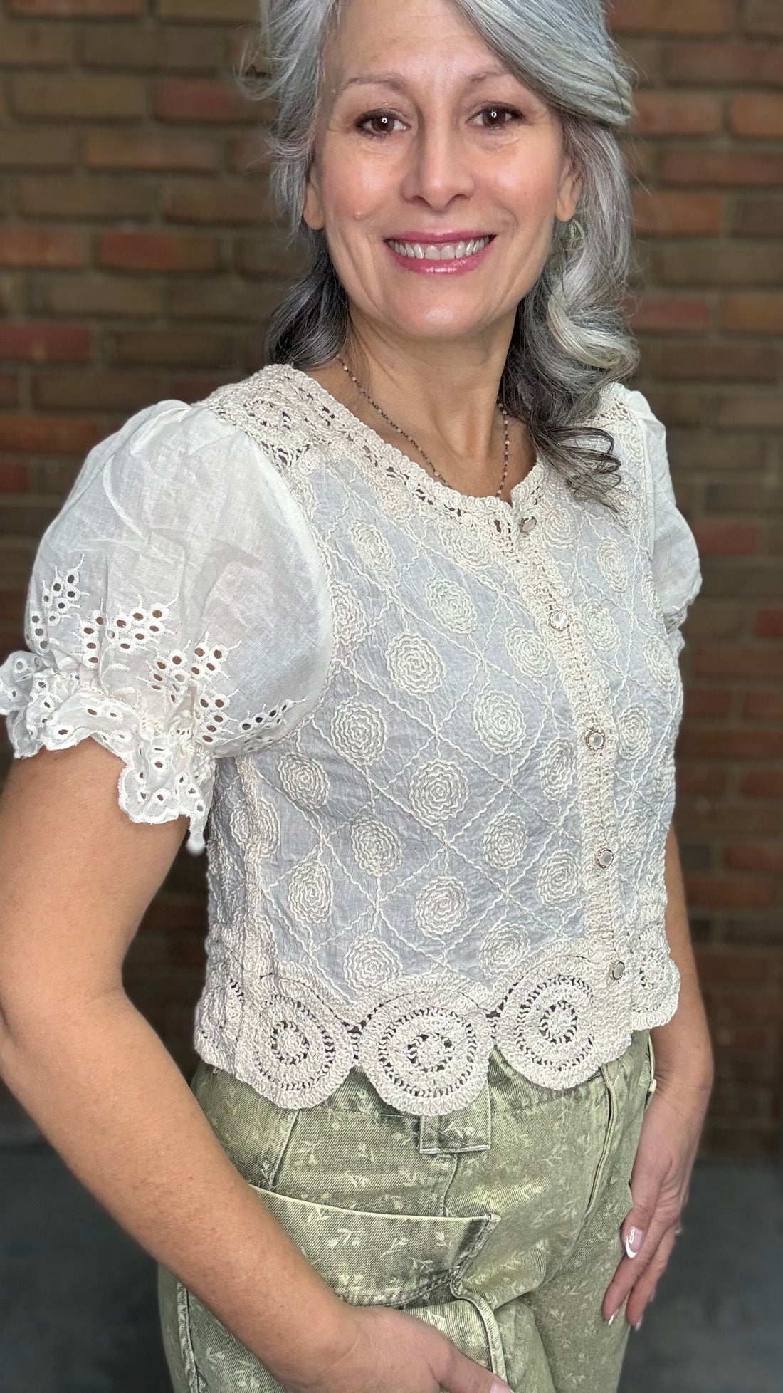 Woman wearing the Crochet Embroidery Button-Up Top and Floral Printed Barrel Pants with a brick wall background