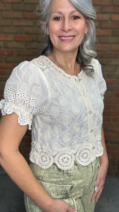 Woman wearing the Crochet Embroidery Button-Up Top and Floral Printed Barrel Pants with a brick wall background