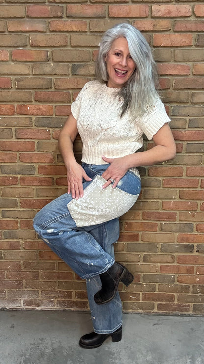 Woman standing in front of a brick wall wearing the Big Pocket Denim Pants and the Oatmeal Sweater Top.