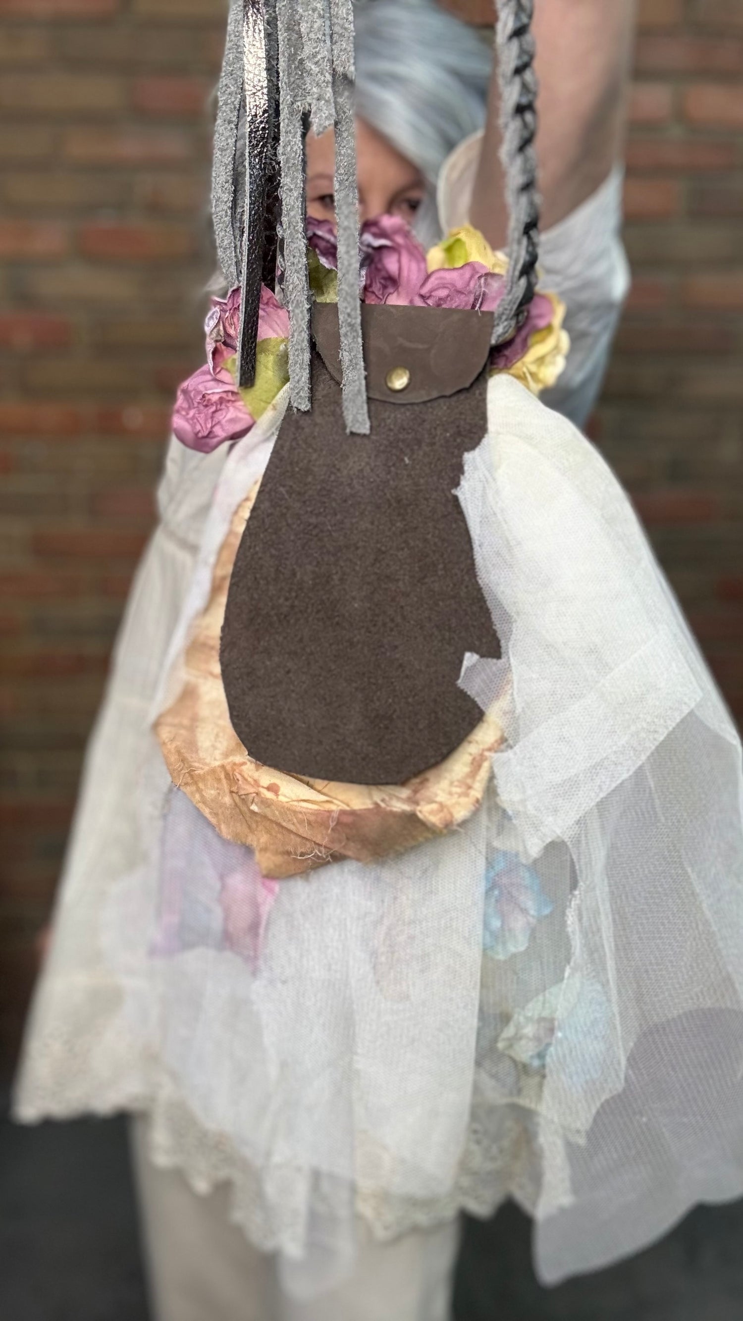 Person wearing a white outfit with Flower Garden Necklace and a cowboy hat against a brick wall.