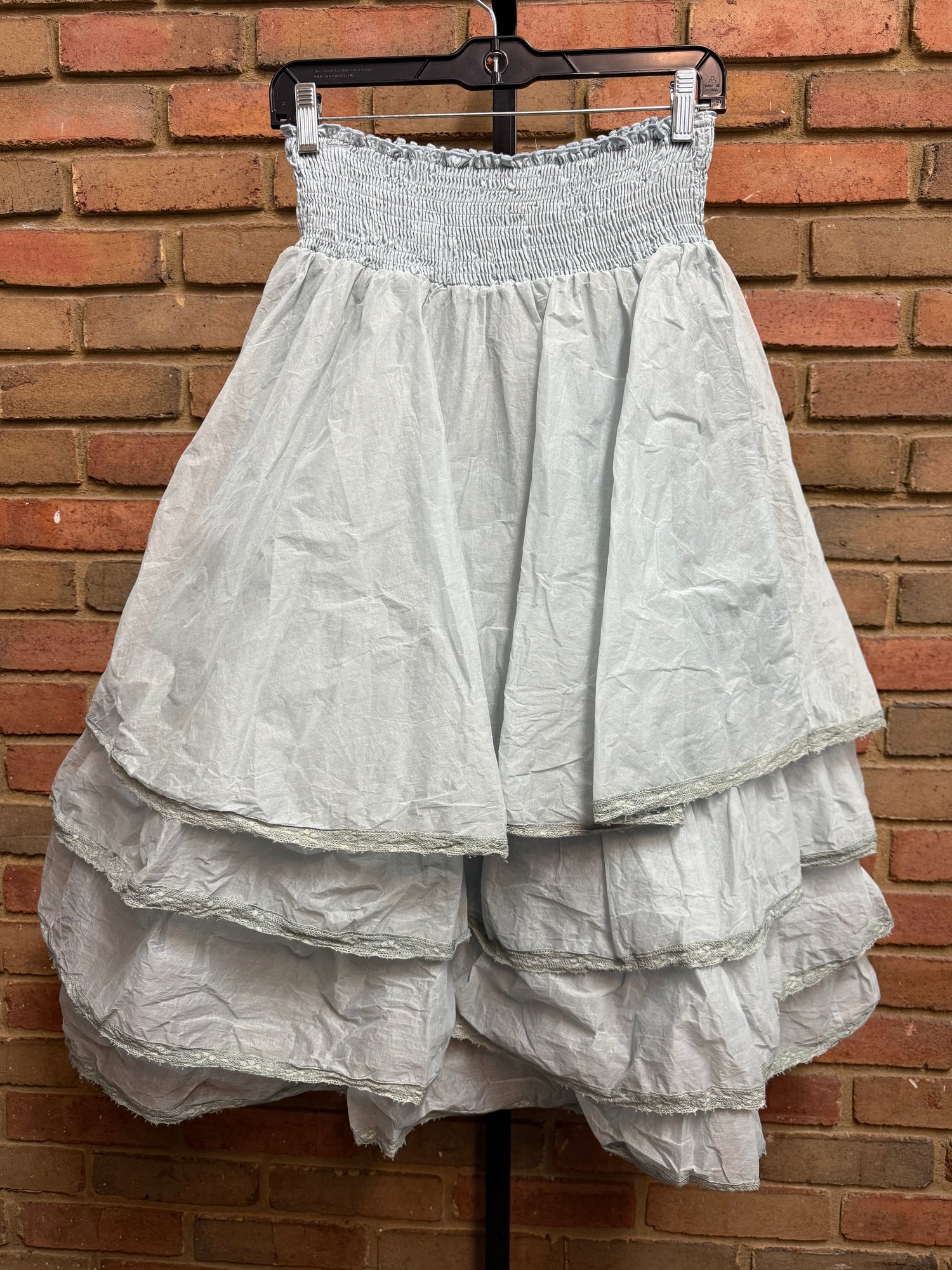 White dress on a hanger against a brick wall